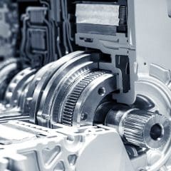 Close-up view of metal gears, shafts, and mechanical components inside an automobile transmission system, showcasing intricate engineering and precision machinery.