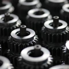 Close-up of multiple metal gears arranged in rows, with a shallow depth of field focusing on the central gears and blurring those in the background.