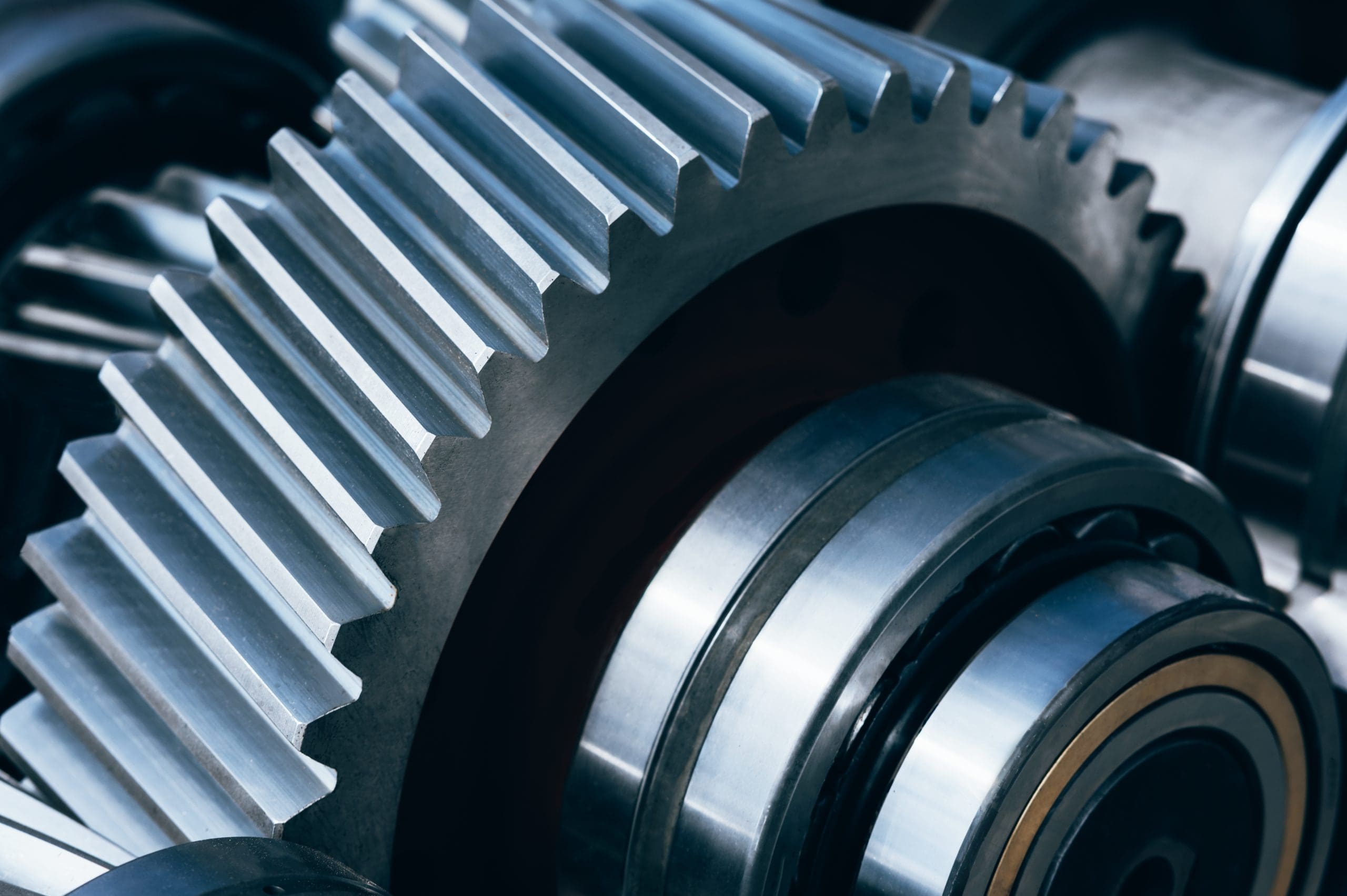Close-up view of shiny metal gears and bearings in a mechanical system, highlighting the precise, angled teeth and polished surfaces of the machinery components.